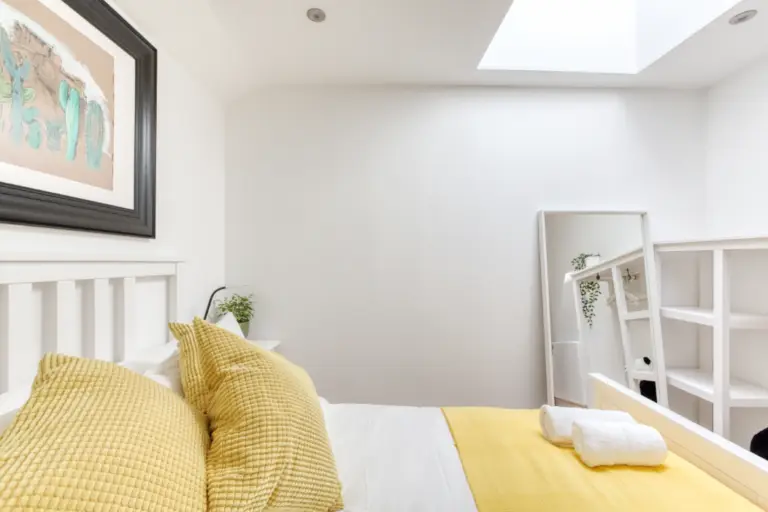 Yellow bed runner and cushions beside white bunk beds