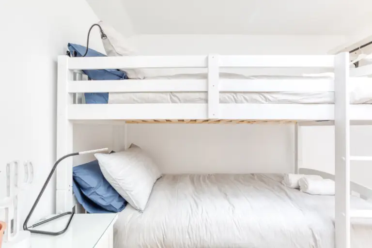 White bunk beds with grey cushions and reading lamps