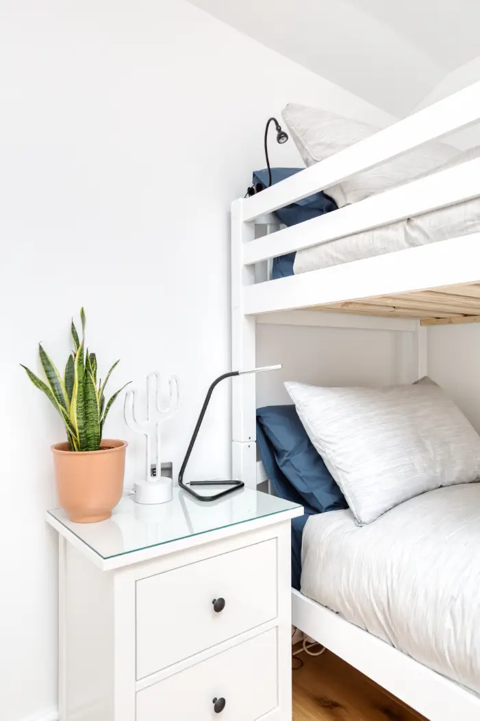 Bunk bedroom with a bedside table and potted plant