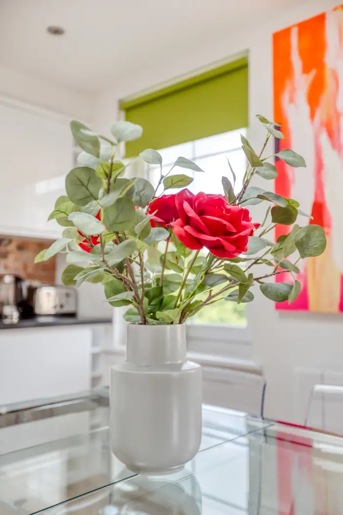 Flowers on a glass dining table beside colourful artwork