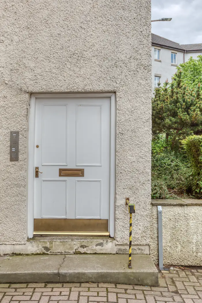 White entrance door beside stone paving at a Caledonian apartment
