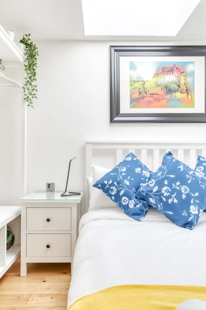 Blue patterned cushions and framed artwork above a double bed