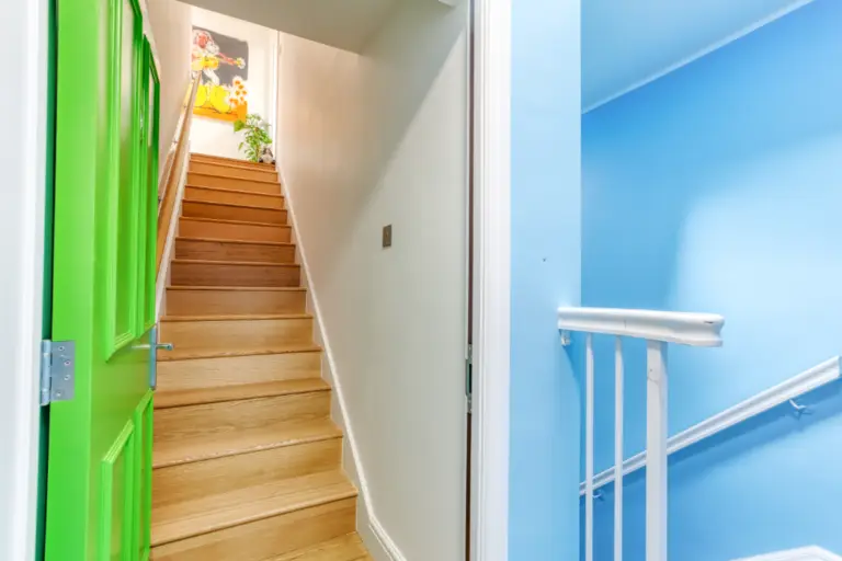 Wooden staircase with blue walls and a green doorway