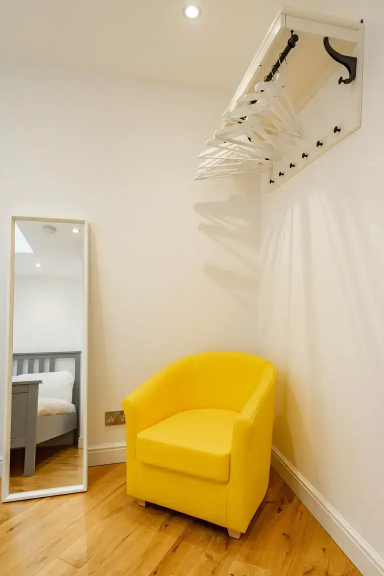 Yellow armchair beneath wall-mounted coat hooks