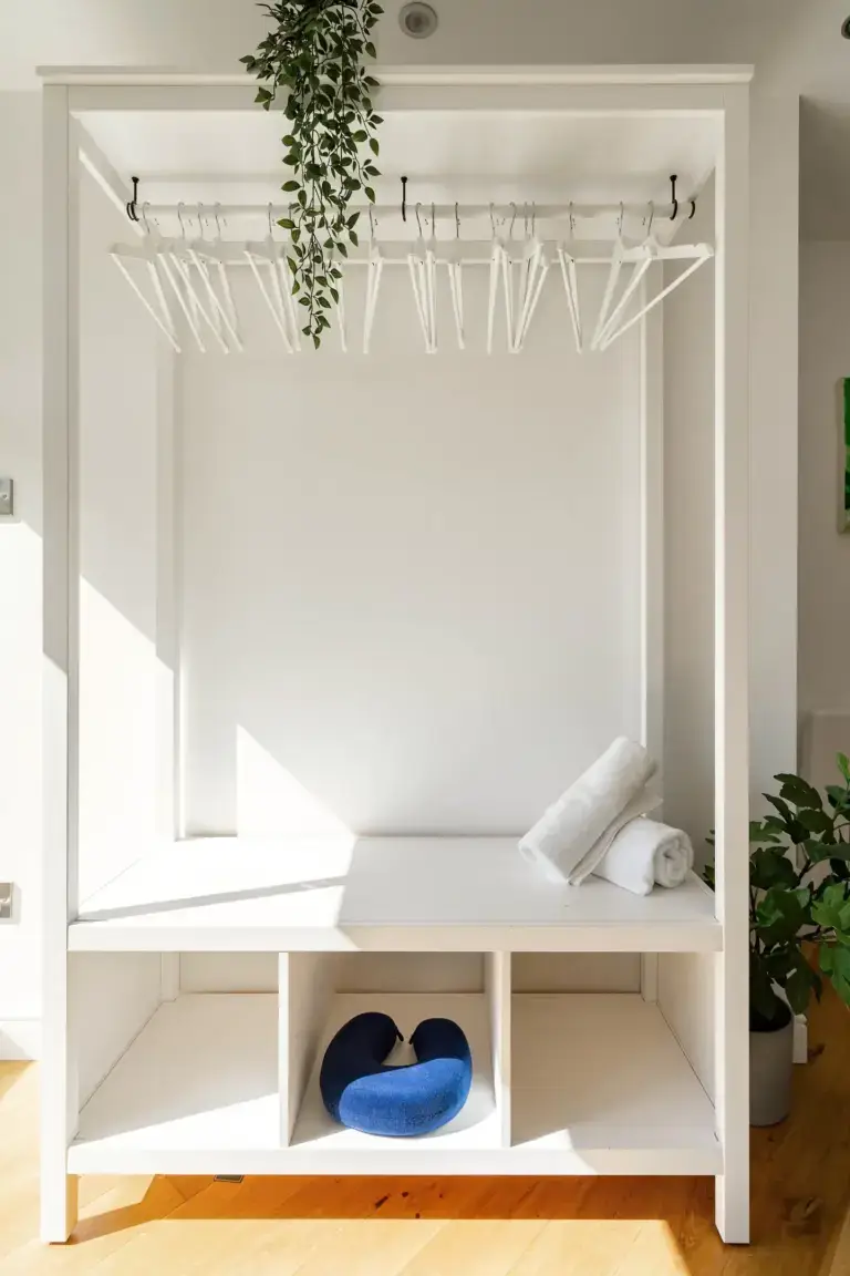 White hallway bench with coat hooks and trailing greenery