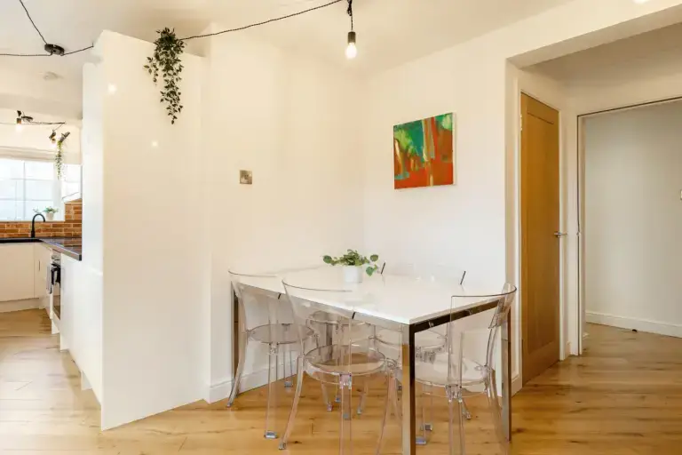 Glass dining table beside a white apartment kitchen