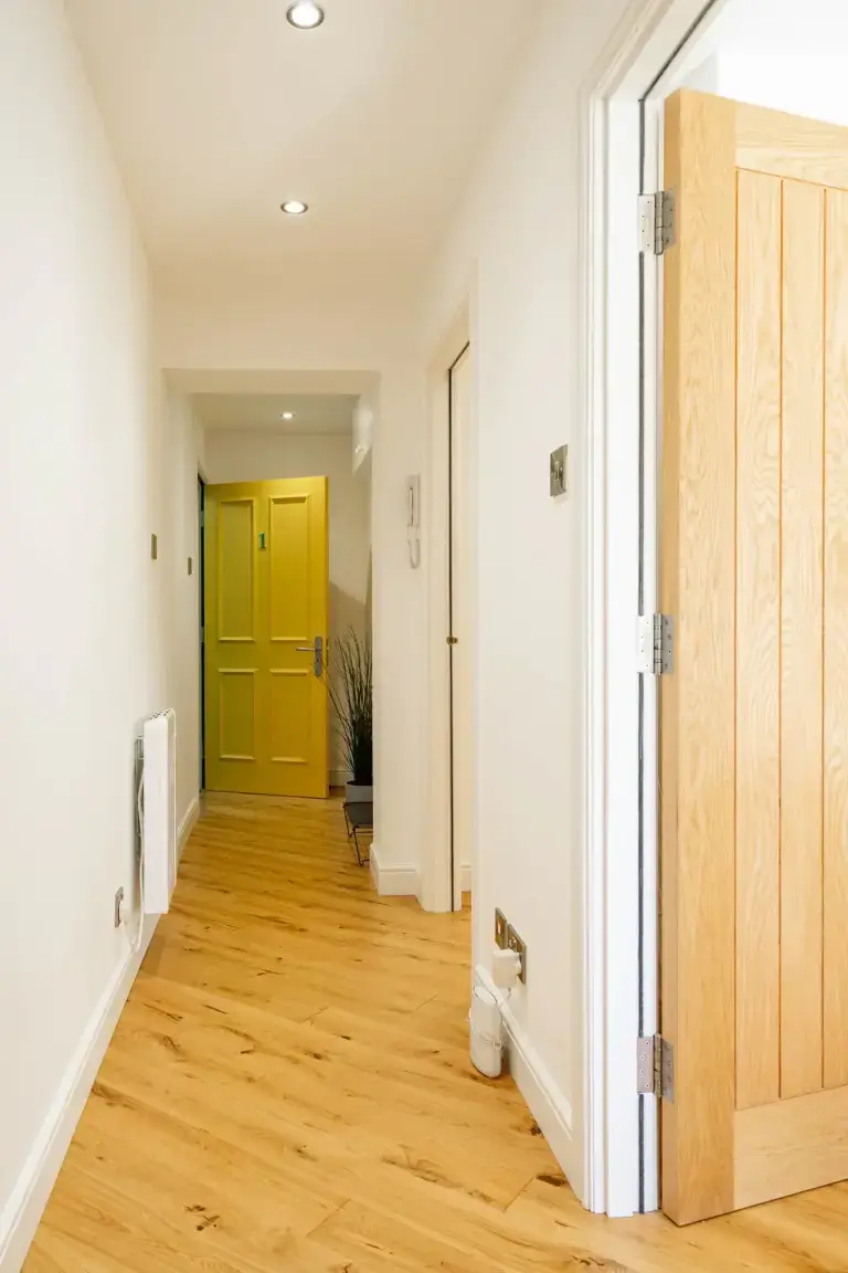 Wood-floored hallway with a yellow door