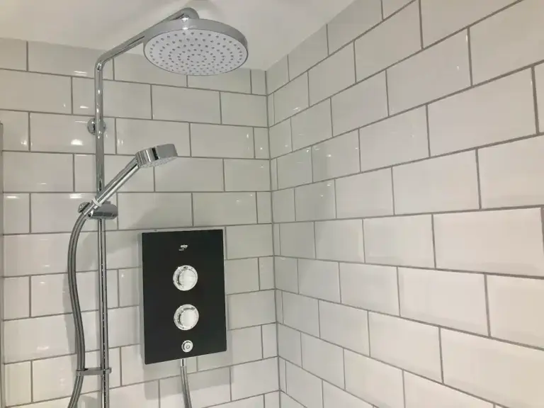 Rainfall shower and controls against white tiled walls